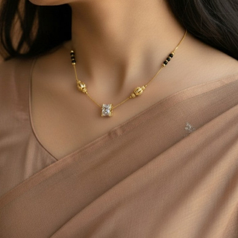 Gold necklace with a diamond pendant worn by a model in a beige outfit