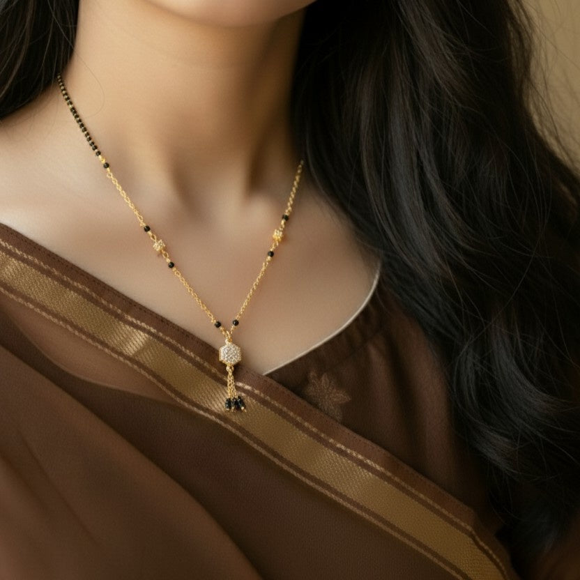Woman wearing a gold necklace with black beads and gemstones.