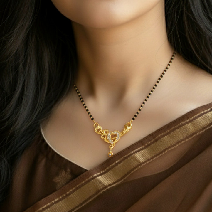 Gold necklace with a heart design on a model wearing a brown saree.