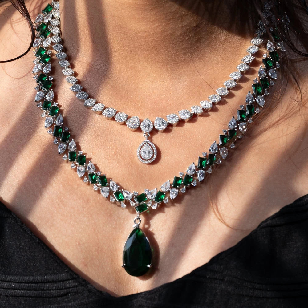 Close-up of a woman wearing a luxurious emerald and diamond necklace.