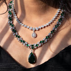 Close-up of a woman wearing a luxurious emerald and diamond necklace.