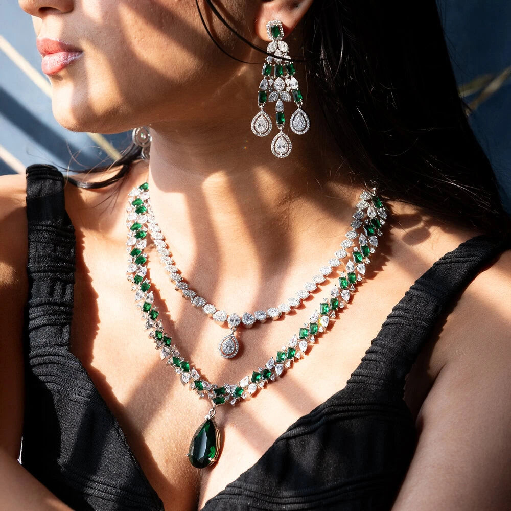 Close-up of a woman wearing a green and white gemstone necklace and earrings.