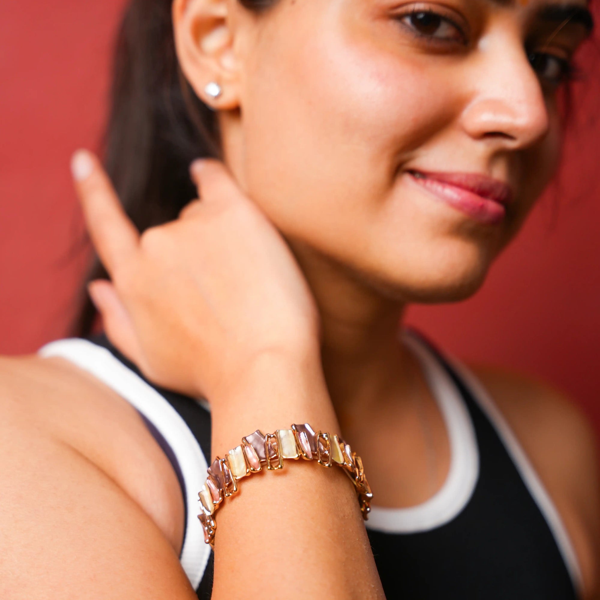Woman wearing a gold bracelet with a blurred red background