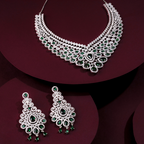 Ornate necklace and earrings with green gemstones on a dark red background