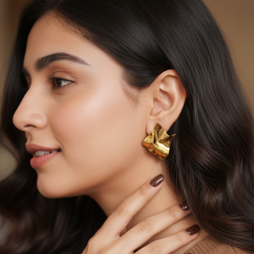 Woman wearing gold earrings with a neutral background