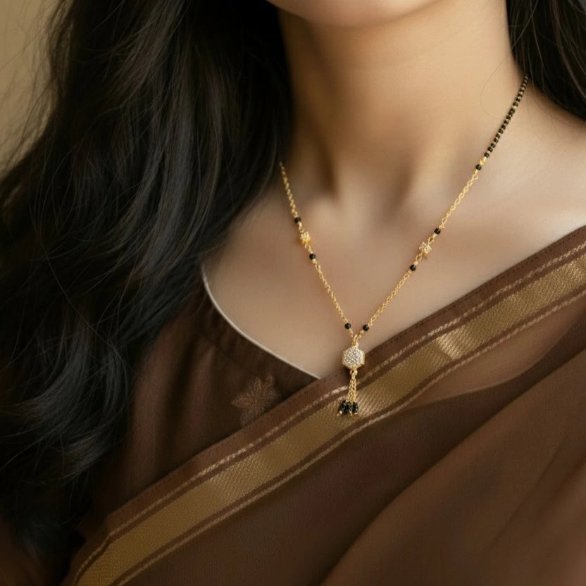 Woman wearing a gold necklace with black beads and a pendant.