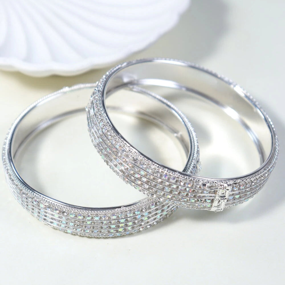Two silver bangles with intricate designs on a white background