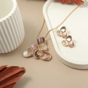 Elegant floral jewelry set featuring a multi-petal necklace and matching earrings in rose gold, blush pink, cream, and mauve tones, displayed on a minimal beige and white background with modern decor elements.