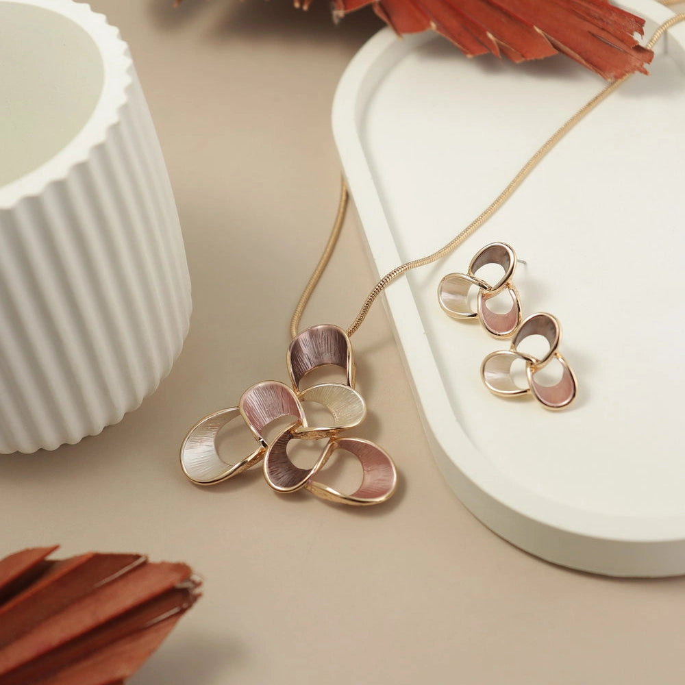 Rose gold and pink floral earrings on a beige surface with decorative elements.