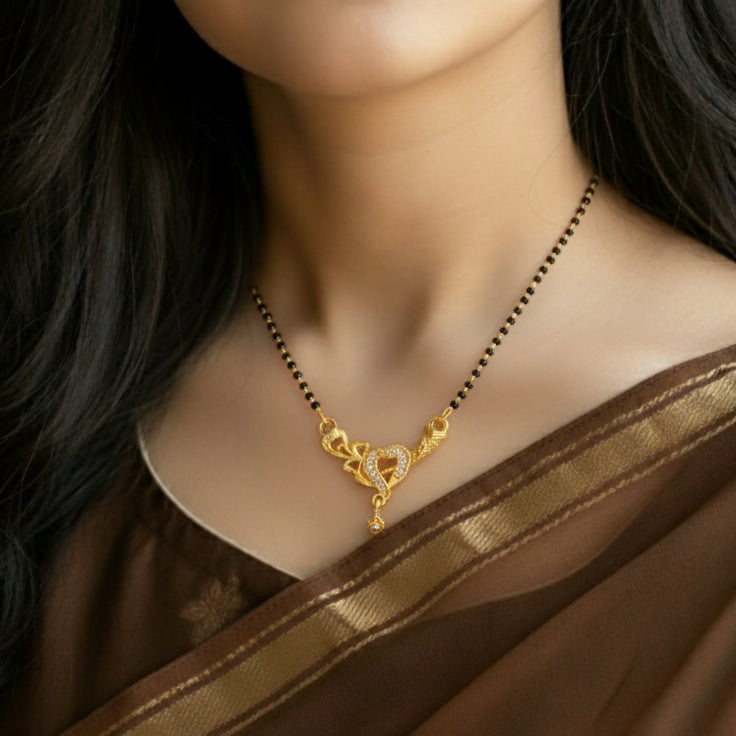 Gold necklace with a heart pendant on a model wearing a brown saree.