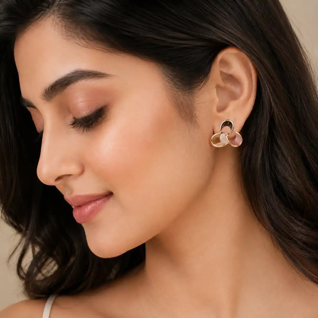A close-up of a woman wearing a small gold-toned hoop earring with a pink floral accent, shown against her ear and dark hair. jewelry Online