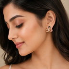 A close-up of a woman wearing a small gold-toned hoop earring with a pink floral accent, shown against her ear and dark hair. jewelry Online