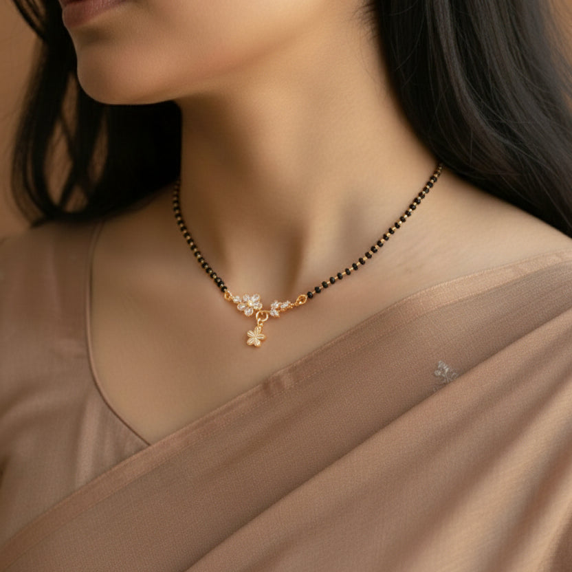 Woman wearing a delicate necklace with black beads and gold accents.