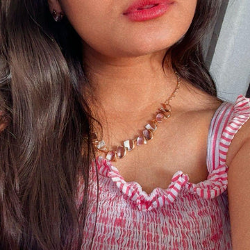 Woman wearing a pink and white patterned dress with a neutral background also knot set