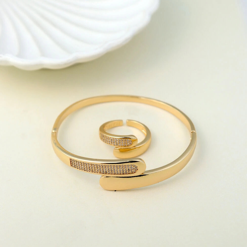 Gold bracelet and ring set on a light background