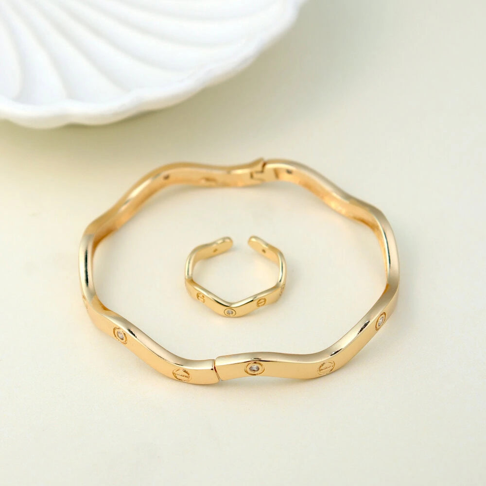 Gold bracelet and ring set on a light beige background