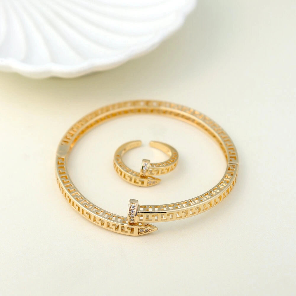 Gold bracelet and ring set on a light background