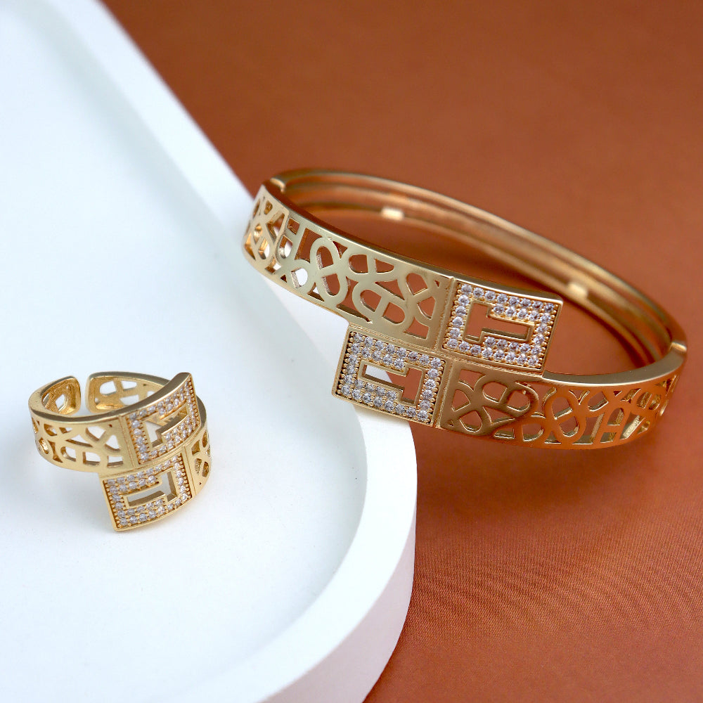 Exquisite gold-plated bangle and ring set with intricate latticework and sparkling cubic zirconia embellishments. A perfect blend of traditional elegance and modern statement jewelry for weddings, festive occasions, and luxury gifting.filigree bracelet, adjustable statement ring, ethnic-inspired jewelry, bridal bangle set.