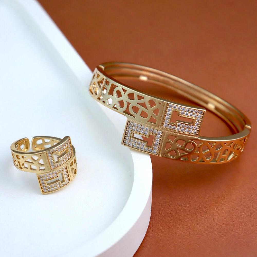 Gold bracelet and ring with intricate designs on a white and brown background