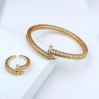 Gold bracelet and ring set on a white surface