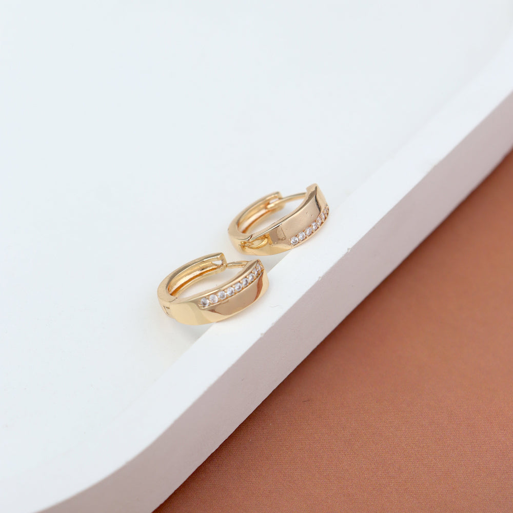 Elegant gold-toned huggie hoop earrings with a sleek, modern design, featuring a row of sparkling American diamonds. Displayed on a white and brown background, highlighting their timeless and sophisticated appeal.