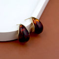Tortoiseshell earrings with gold accents on a white surface