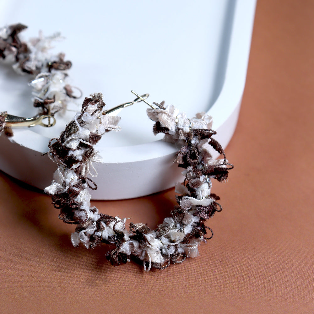 Handmade bohemian-style fabric-woven hoop earrings in earthy brown and cream tones, featuring intricate textured details and gold-tone clasps. Perfect for statement jewellery lovers, artisanal fashion accessories, and trendy ethnic-inspired earrings.
