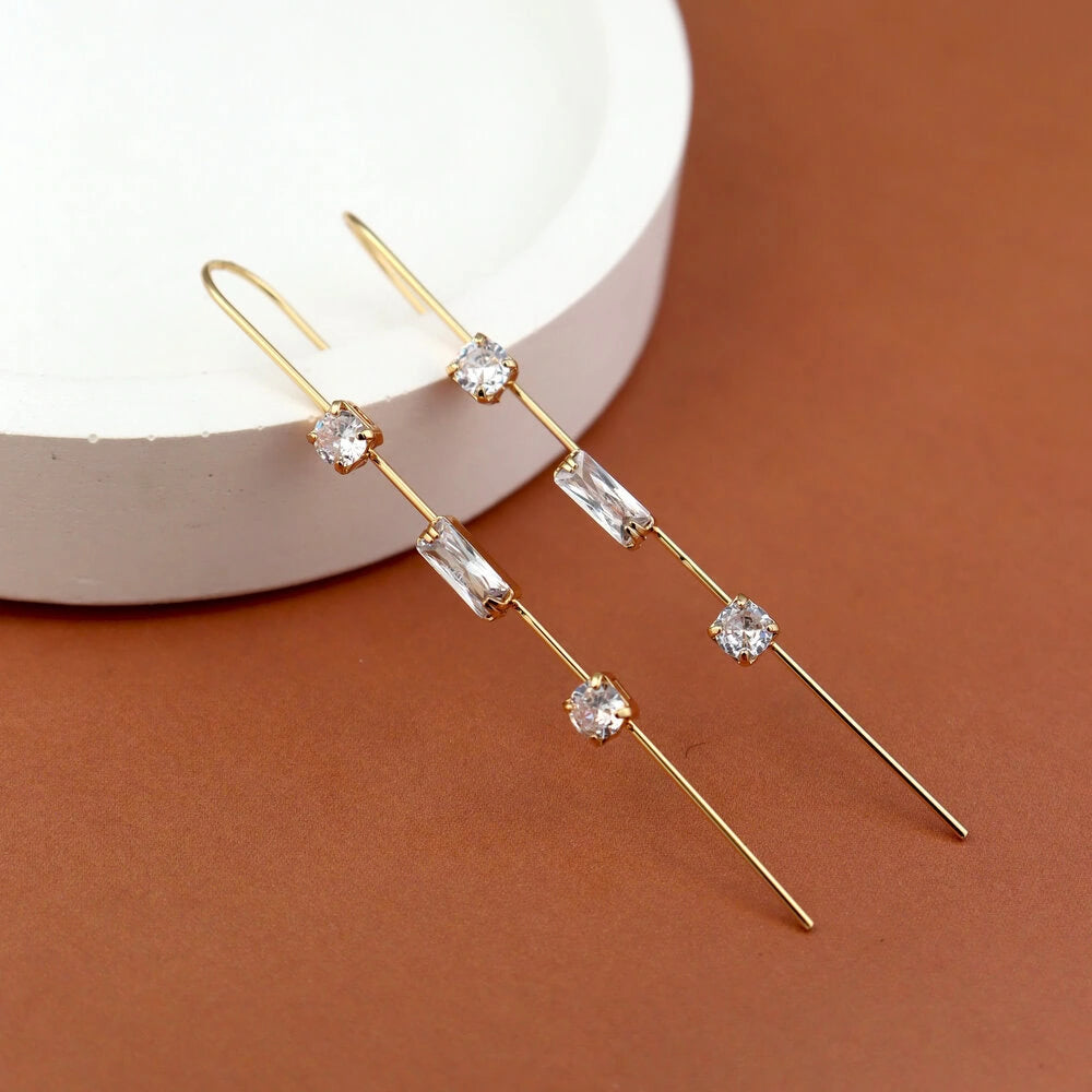 Gold earrings with clear stones on a brown surface