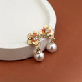 Stylish floral pearl drop earrings for women – gold-plated designer fashion jewellery with enamel finish and crystal stones, perfect for wedding, festive and party wear.
