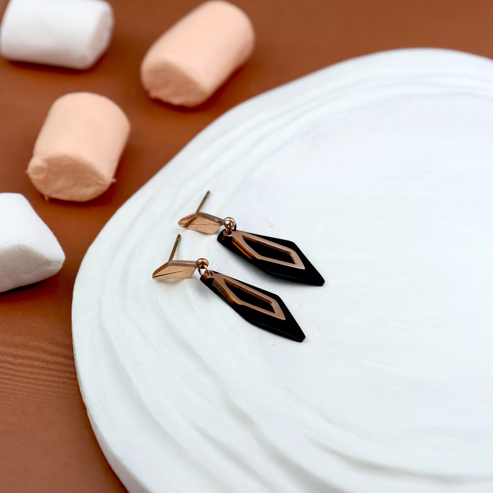 Chic black and rose gold geometric drop earrings featuring a sleek diamond-shaped design. These modern statement earrings add a bold, elegant touch to any outfit—ideal for women’s fashion jewellery, evening wear, and trendy accessories.
