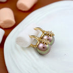 Gold and pearl earring on a white plate with a brown background