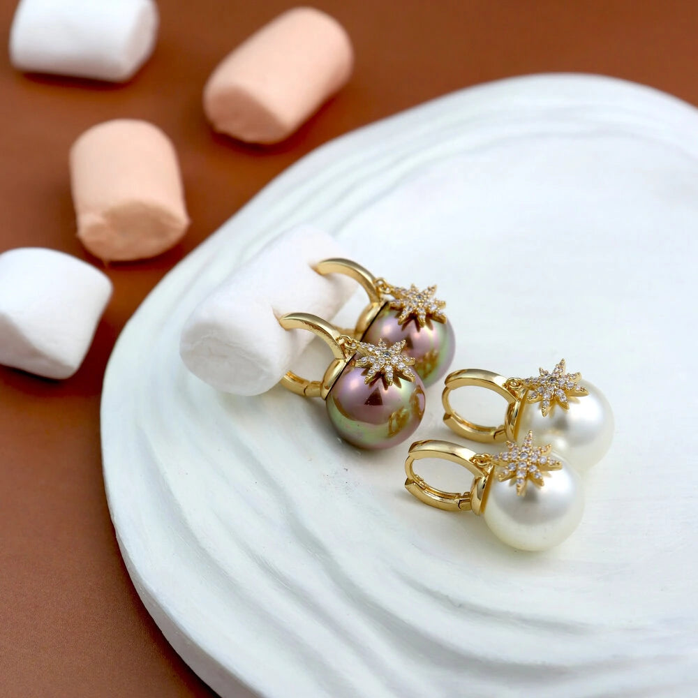 Gold and pearl earrings on a white plate with marshmallows in the background