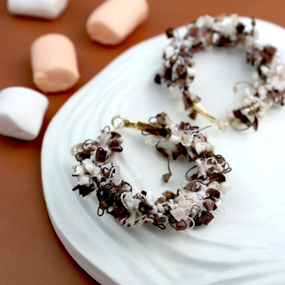 Decorative wreaths with chocolate and coconut on a white plate with marshmallows in the background.