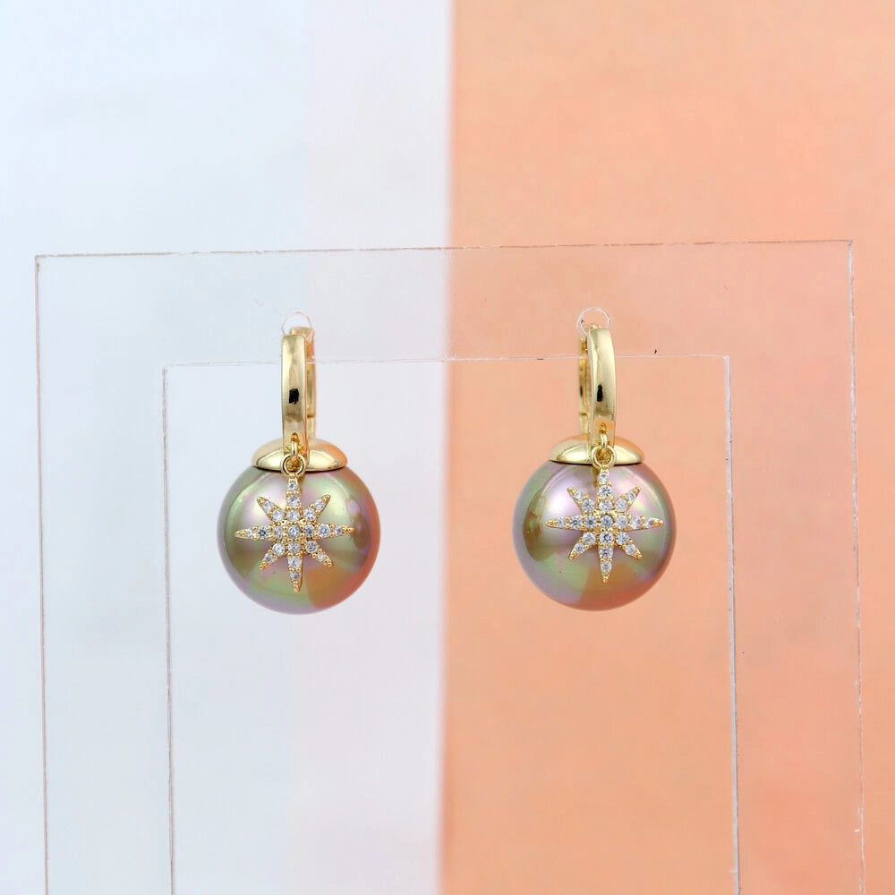 Gold earrings with greenish pearls on a clear stand against a gradient background
