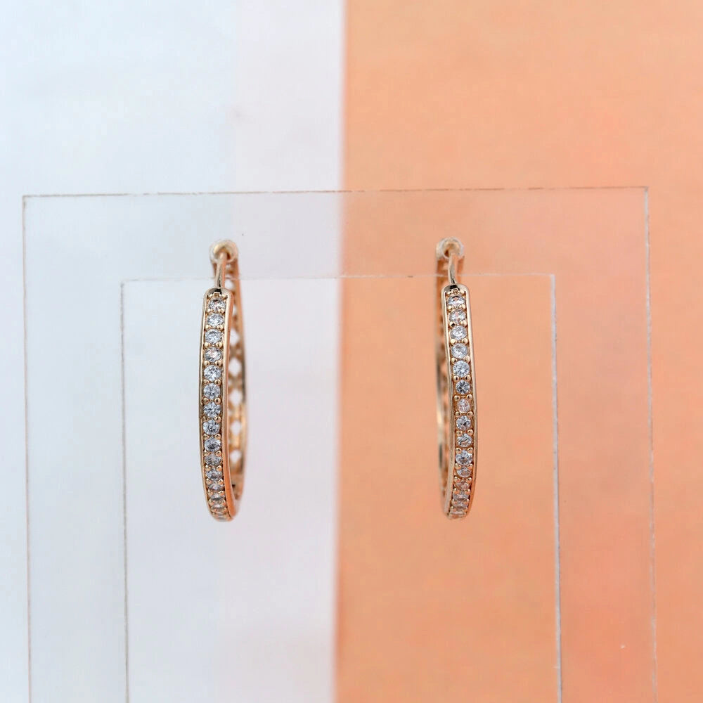 Rose gold hoop earrings on a clear stand with a gradient background