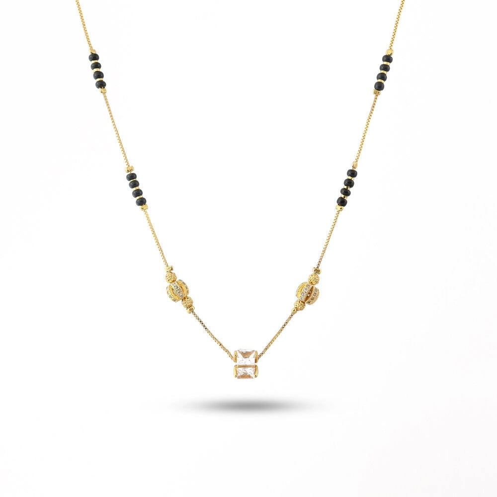 Gold necklace with black beads on a white background