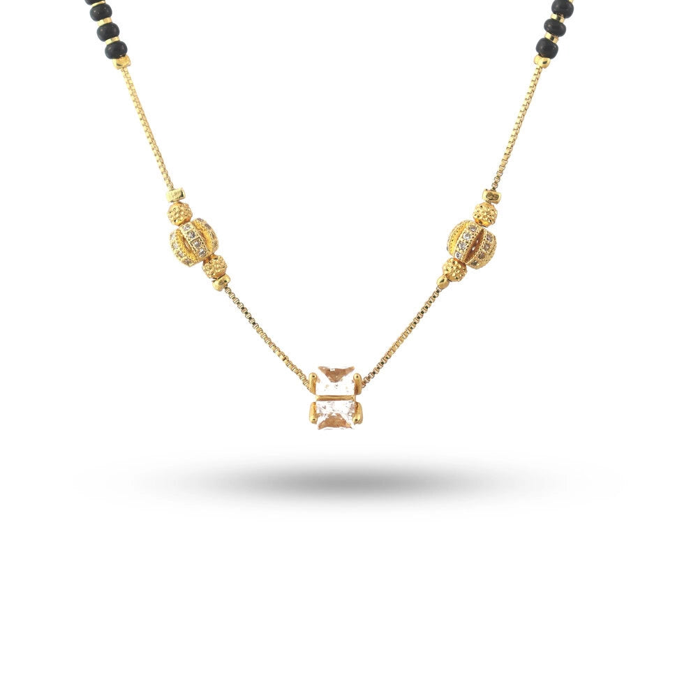 Gold necklace with black beads on a white background