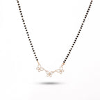 Necklace with black beads and a gold floral pendant on a white background