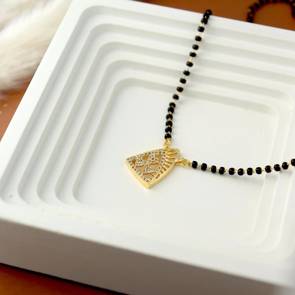 Necklace with a gold pendant on black beads on a white dish