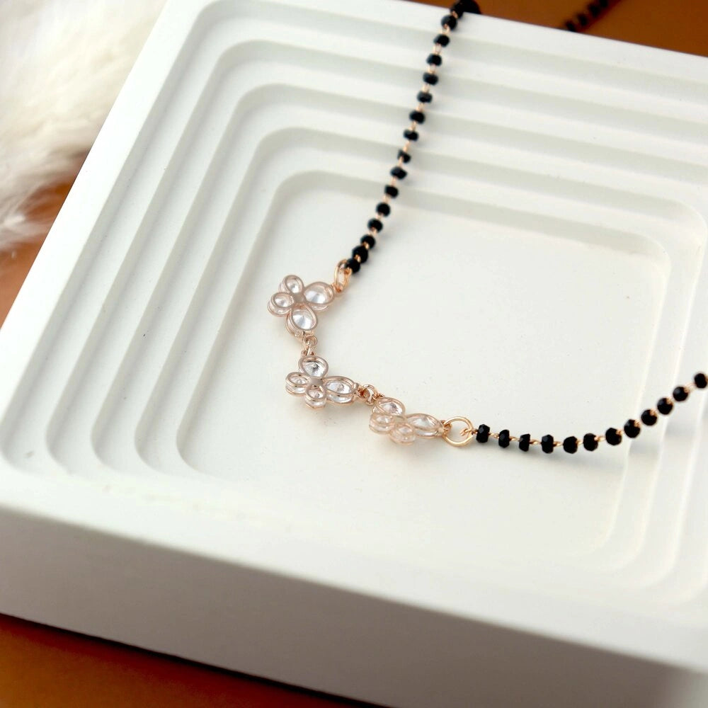 Necklace with black beads and rose gold accents on a white dish
