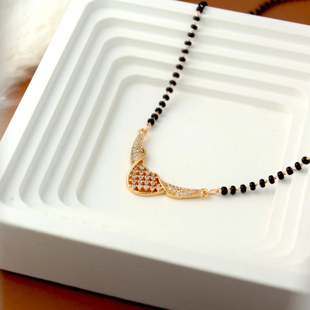 Gold necklace with black beads on a white dish