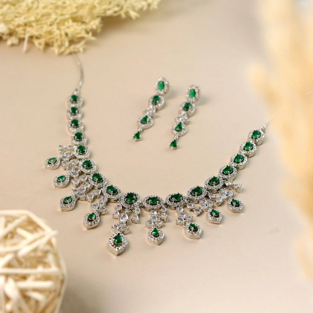 Jewelry set with necklace and earrings featuring green gemstones on a beige background