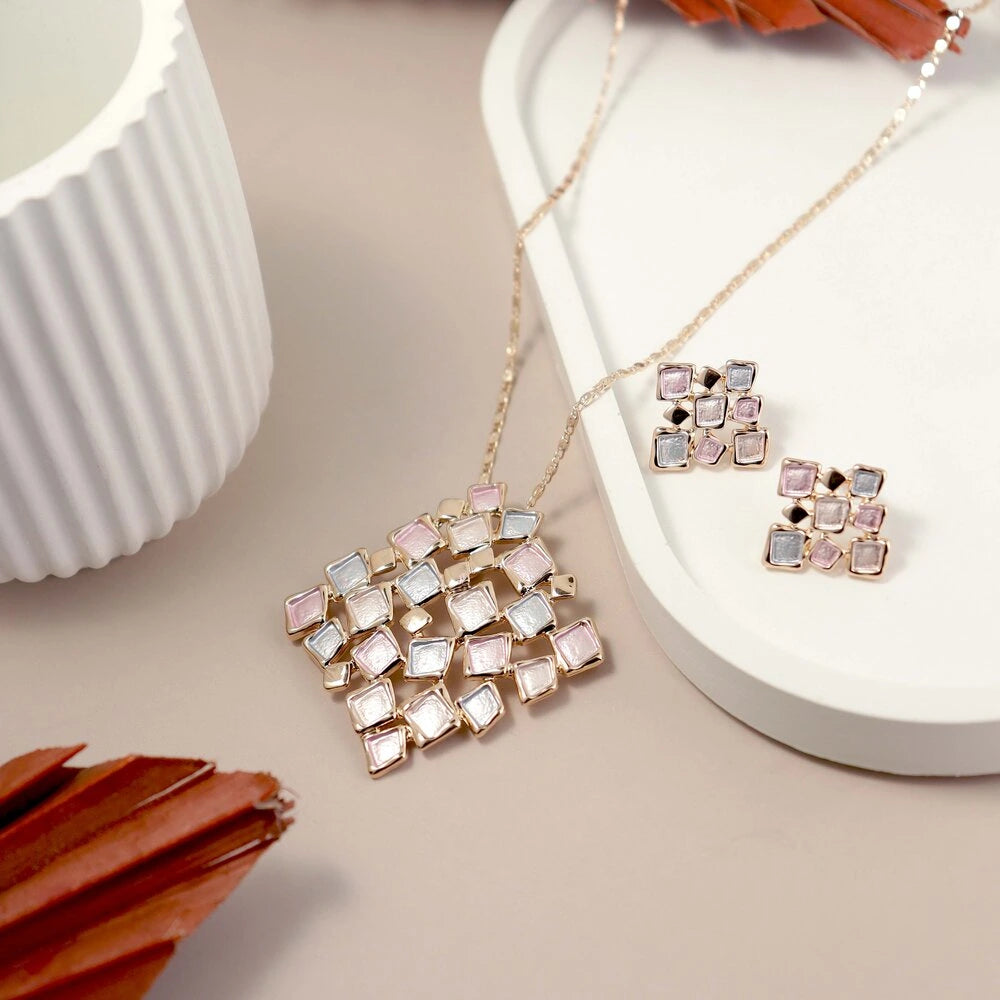 Jewelry set with pink and white geometric design on a beige surface with a white container.