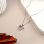 Heart-shaped diamond pendant on a chain against a neutral background