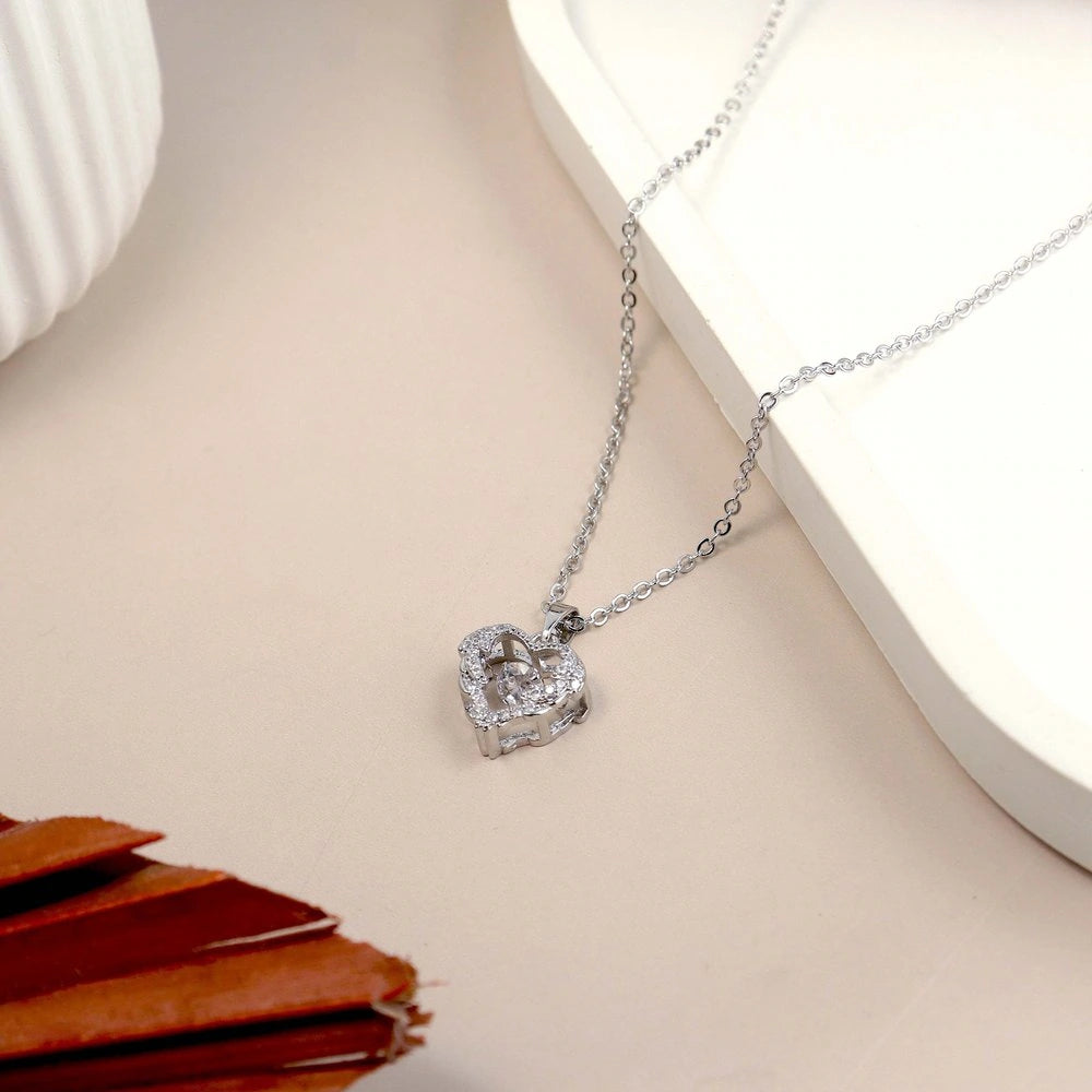 Heart-shaped diamond pendant on a chain against a neutral background