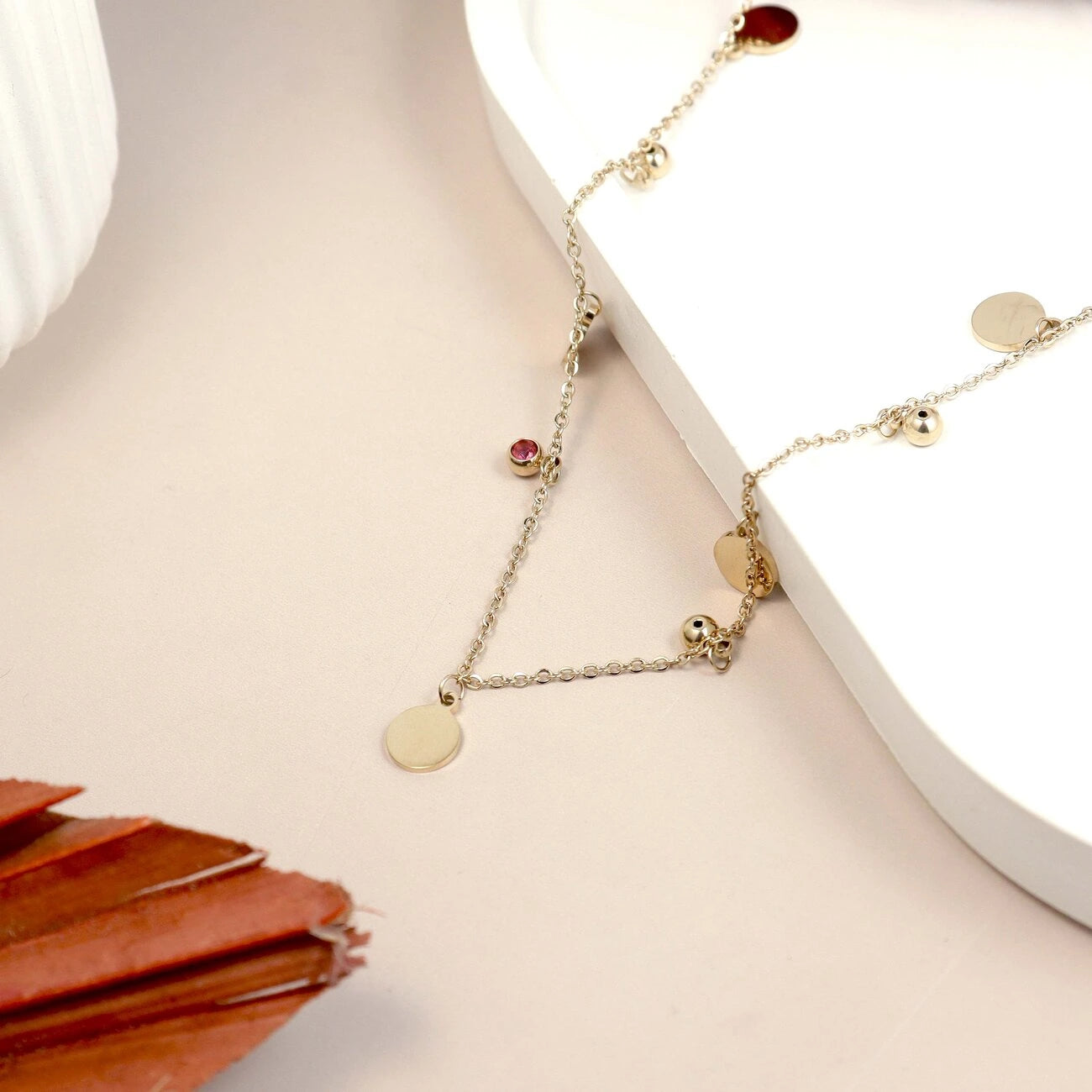 Gold necklace with round pendants on a light surface