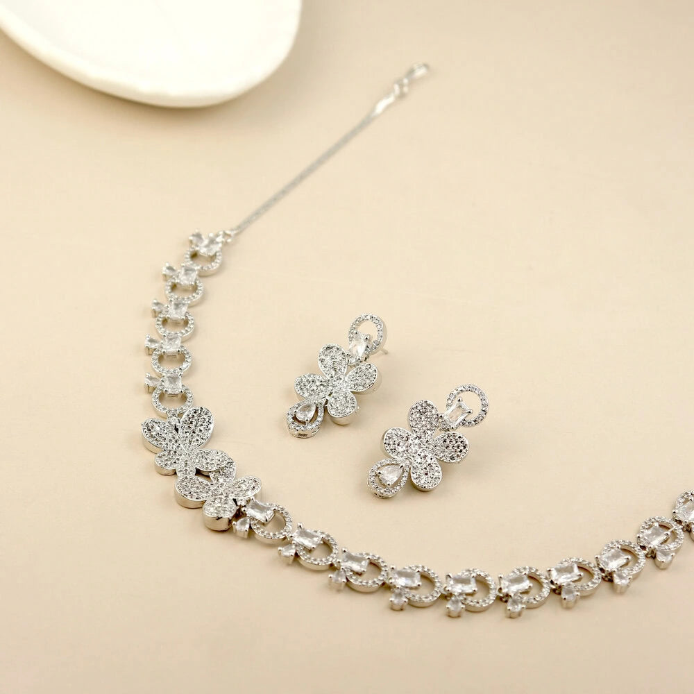 Silver jewelry set with necklace and earrings on a beige background